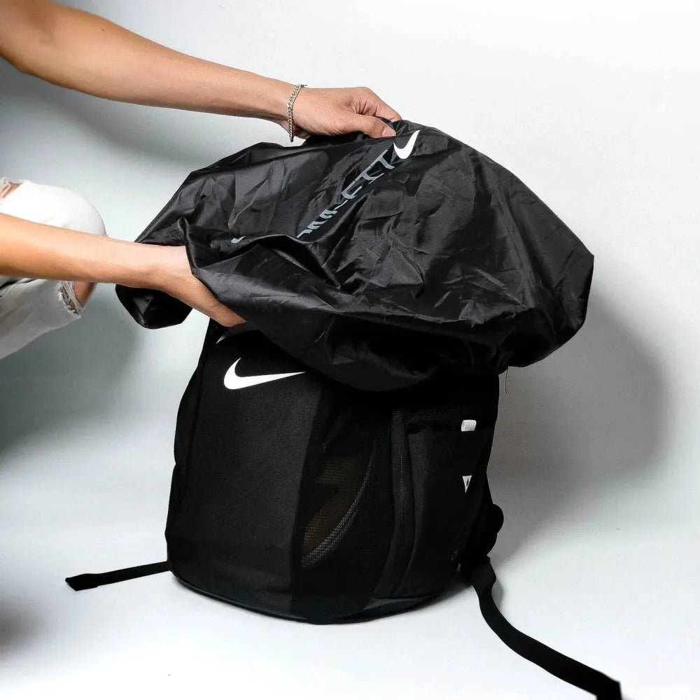 Black Nike backpack being held open on a white background